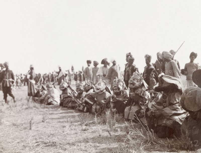 Masked 'devil dancers' at Coronation Durbar, 1903. A group of 'lamas' (Buddhist monks) sit in a row on the ground wearing large, elaborate masks, as they prepare to perform a 'devil dance' at the Coronation Durbar. Delhi, India, circa 1 January 1903. Delhi, Delhi, India, Southern Asia, Asia.