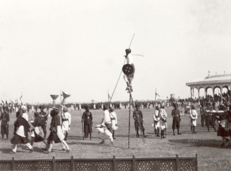 Performers at Coronation Durbar, 1903. Performers from Kutch State enter the pavilion arena at Edward VII's Coronation Durbar. Amongst the group of performers are musicians playing silver trumpets and a stilt walker. Delhi, India, circa 1 January 1903. Delhi, Delhi, India, Southern Asia, Asia.