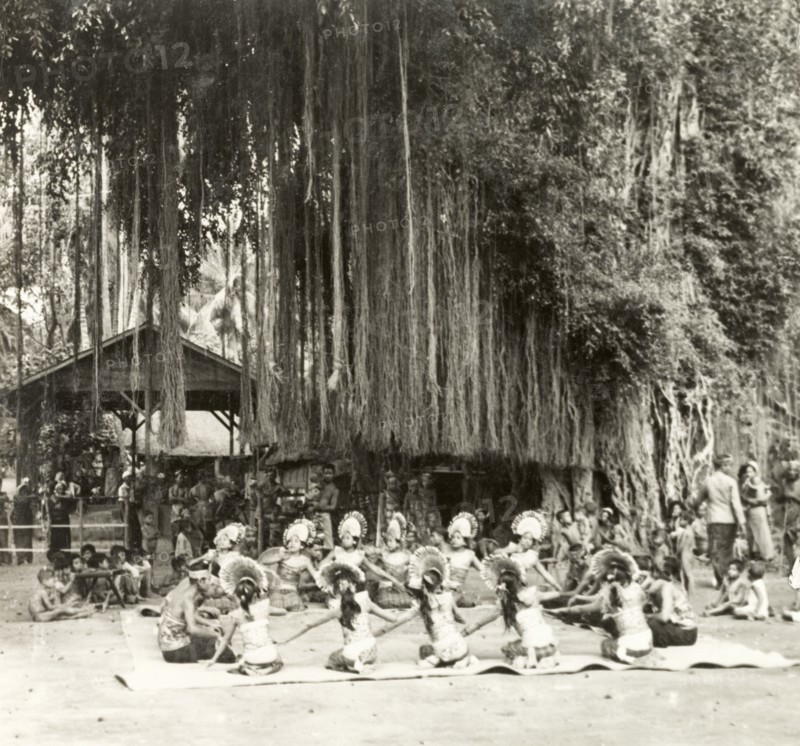 A traditional Balinese dance. Young Balinese men and women sit in a circle as they perform a traditional dance. They wear elaborate costumes, the men adorned with head bands and the women with fanned headdresses. Bali, Indonesia, July 1940., Lesser Sunda Islands (including Bali), Indonesia, South East Asia, Asia.