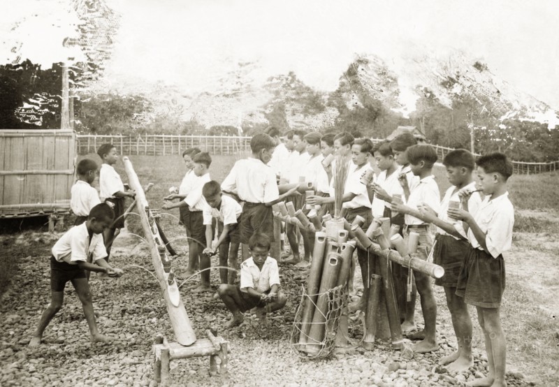 Schoolchildren washing at Keningau Health Centre. Schoolchildren wash their hands and clean their teeth using bamboo wash stands made by trainee health officers at Keningau Health Centre. An original caption notes that the toothbrushes the children use are made from coconut husks. Keningau, North Borneo (Sabah, Malaysia), circa 1937. Keningau, Sabah (North Borneo), Malaysia, South East Asia, Asia.
