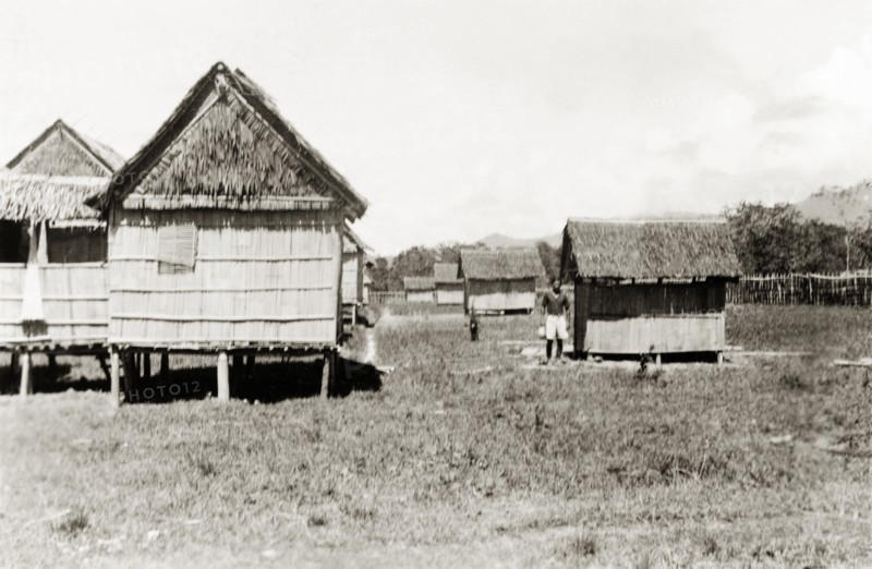 New housing, North Borneo. View of a row of new stilted, bamboo houses with accompanying outhouses. The buildings were built by North Borneo Medical Services as part of a health campaign to introduce new hygiene and sanitation practices to local villages. Keningau, North Borneo (Sabah, Malaysia), circa 1937. Keningau, Sabah (North Borneo), Malaysia, South East Asia, Asia.