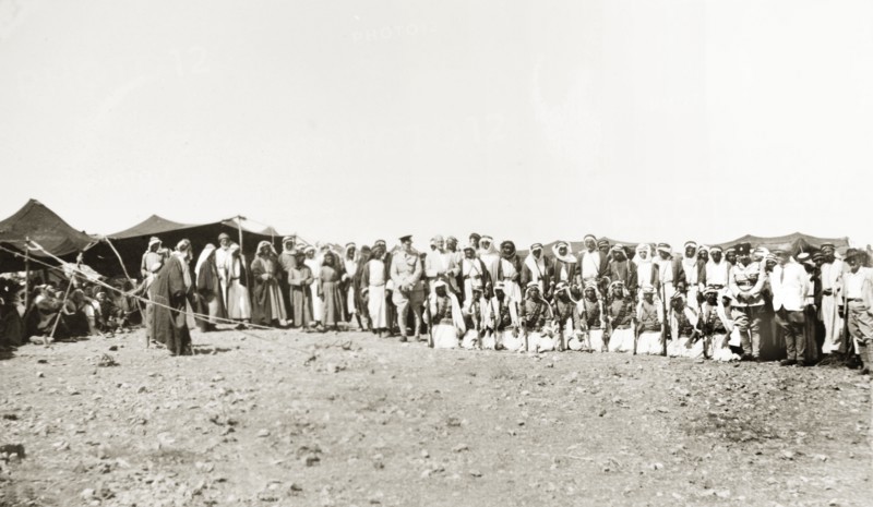 A meeting with Arab leaders. Two British officials pose for a group portrait with Arab leaders during a meeting at a desert camp. A line of armed Arab men kneel in the front row. British Mandate of Palestine (Israel), circa 1940. Israel, Middle East, Asia.