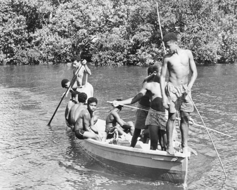 Boys in a canoe, Fiji. A group of boys in shorts relax in the sun as they pilot a canoe along a river. Levuka, Ovalau, Fiji, 1965. Levuka, Ovalau, Fiji, Pacific Ocean, Oceania.