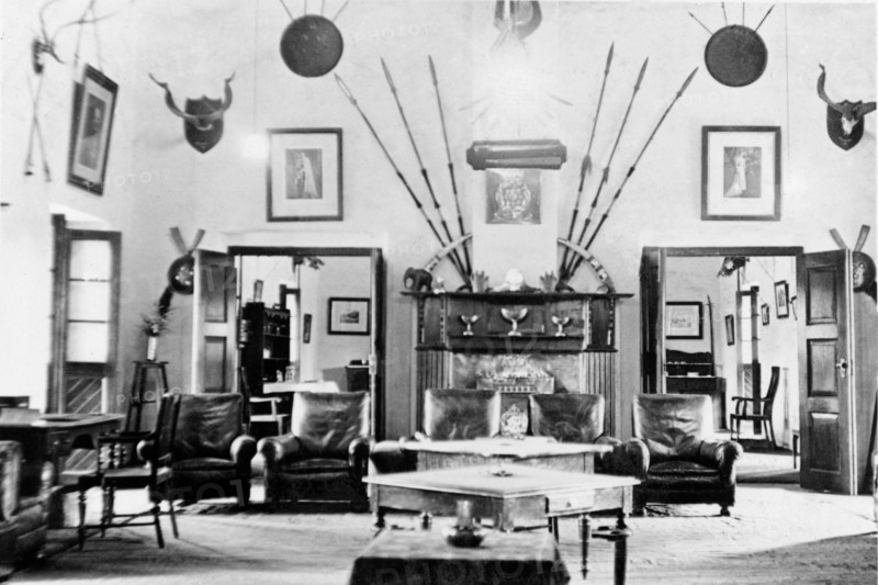 Drawing room at the Police Training School. Interior shot of the Mess inside the Police Training School at Moradabad. Hung on the wall, above a grand fireplace and five leather armchairs, are several framed portraits and numerous spears, shields and hunting trophies. Moradabad, United Provinces (Uttar Pradesh), India, circa 1933. Moradabad, Uttar Pradesh, India, Southern Asia, Asia.