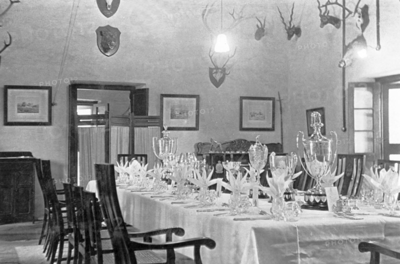 Dining room at the Police Training School. Various trophies form the centrepiece of a table that has been set for a formal dinner for the Inspector-General of Police, Harold Poe, at Moradabad's Police Training School. The wall behind is decorated with framed pictures and hunting trophies. Moradabad, United Provinces (Uttar Pradesh), India, circa 1933. Moradabad, Uttar Pradesh, India, Southern Asia, Asia.