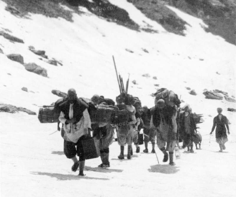 Final ascent to the peak of Sheshnag Mountain. A group of mountain guides make their final ascent to the snow-capped peak of Sheshnag Mountain, carrying bulky loads on their backs with puttees to protect their legs. Jammu and Kashmir, India, 1934., Jammu and Kashmir, India, Southern Asia, Asia.