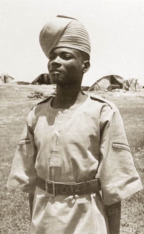 Portrait of an Arab 'onbashi'. An Arab 'onbashi' (corporal) stands to attention, wearing military uniform and a 'pagari' (turban). His exact regiment is unknown, but related information suggests he belongs to either the Somaliland Scouts, the Sudan Defence Force or, perhaps most likely, the Aden Protectorate Levies. Possibly Aden, Yemen, circa 1957. Aden, Adan, Yemen, Middle East, Asia.
