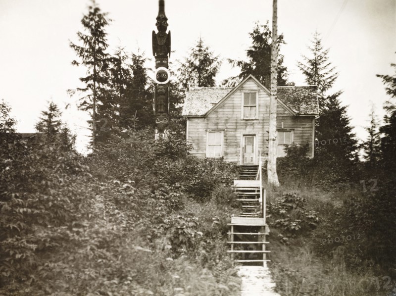 A traditional Tlingit house. A traditional Tlingit house and totem pole, located in a forest on Wrangell Island. Wrangell, Alaska, United States of America, circa 1931. Wrangell, Alaska, United States of America, North America, North America .
