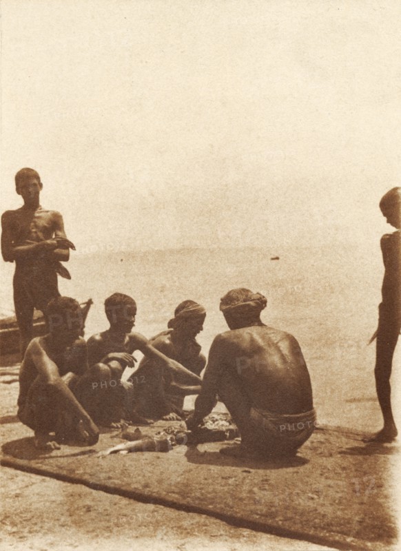 Boatmen on the breakwater. Boatmen cut up fish on the breakwater. Mormugao, Goa, India, circa 1906. Mormugao, Goa, India, Southern Asia, Asia.