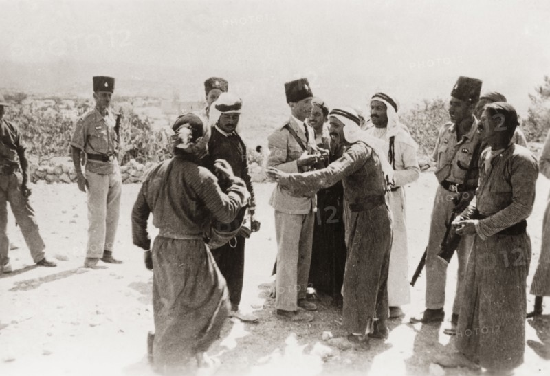 Police questioning Palestinian Arabs, 1938. Armed officers of the Palestine Police Force question a group of Palestinian Arab men from a rural village. During the period of the Great Uprising (1936-39), an additional 20,000 British troops were deployed to Palestine in an attempt to clamp down on Arab dissidence. British Mandate of Palestine (Middle East), 1938., Middle East, Asia.