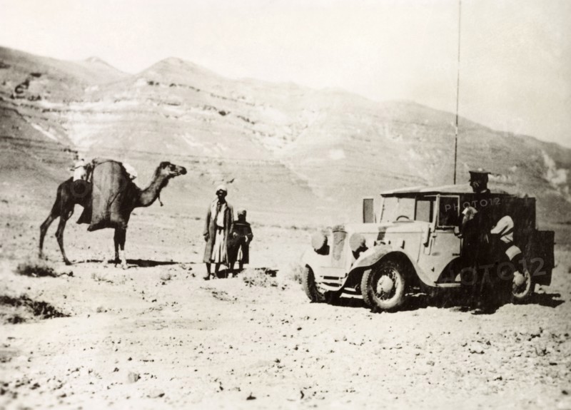 Signaller in the Palestinian desert. A British officer of the Royal Corps of Signals stops his car on a desert road beside an Arab man and a boy travelling with a camel. During the period of the Great Uprising (1936-39), an additional 20,000 British troops were deployed to Palestine in an attempt to clamp down on Arab dissidence. British Mandate of Palestine (Middle East), circa 1938., Middle East, Asia.