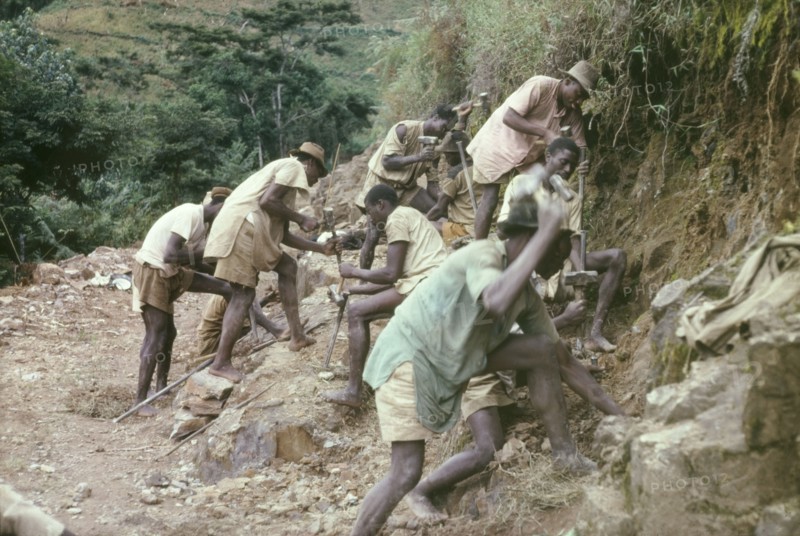 Road building at Mafuga Forest. A group of labourers drill rocks with hand chisels in Ishasha Valley, creating shot holes to be filled with gelignite for blasting. These porters were employed by a forestry team who were clearing a track in Mafuga Forest nursery. Kigezi, South West Uganda, September 1963., West (Uganda), Uganda, Eastern Africa, Africa.