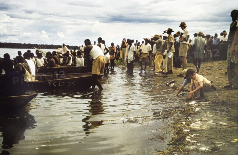 Regatta at Katunguru. Crowds line the banks of the Kazinga Channel to watch a canoe race at the Katunguru regatta. Katunguru, West Uganda, 1957., West (Uganda), Uganda, Eastern Africa, Africa.