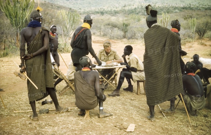 Paying the porters after safari. District Forest Officer James Lang Brown (centre) pays several Suk porters after a survey safari to the Karasuk hills. To his left sits Odong, a Ugandan Forest Guard. Kenya, 1959., East (Uganda), Uganda, Eastern Africa, Africa.