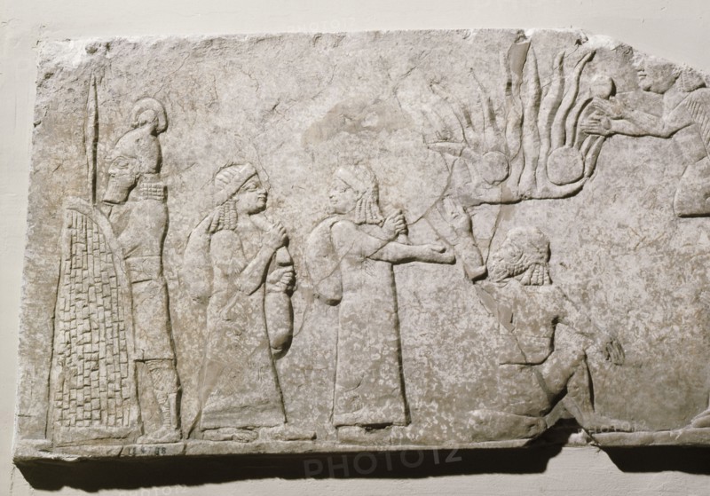 Stone relief depicting Babylonian and Chaldean prisoners in camp, under guard, with a log fire burning behind