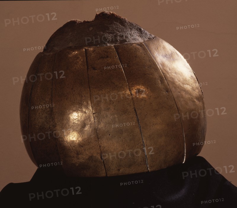 Brass helmet comprised of hammered plates and rondels fixed to a core of human hair and interwoven with twine