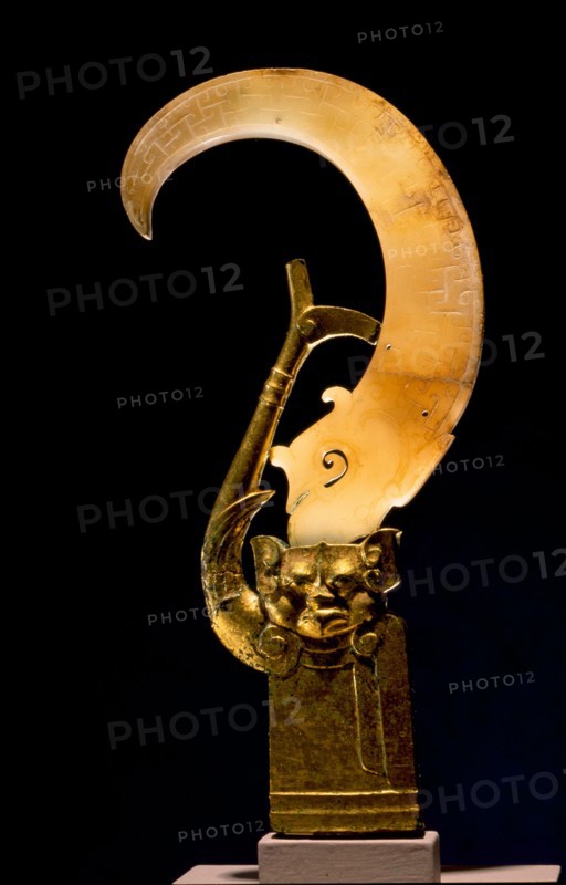 The gilt bronze finial of anthropomorphic appearance was made in the Western Han period to hold the curving jade element which is perhaps a hundred years earlier in date
