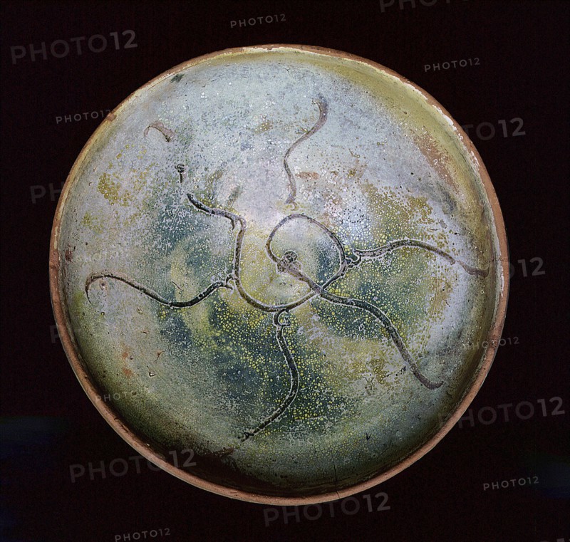 A redware pottery bowl with an abstract design scratched through the white slip before glazing