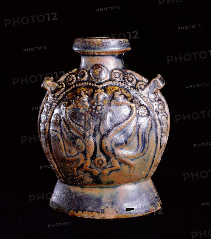 A molded brown glazed flask decorated on one side with a pair of birds surrounded by flowerheads