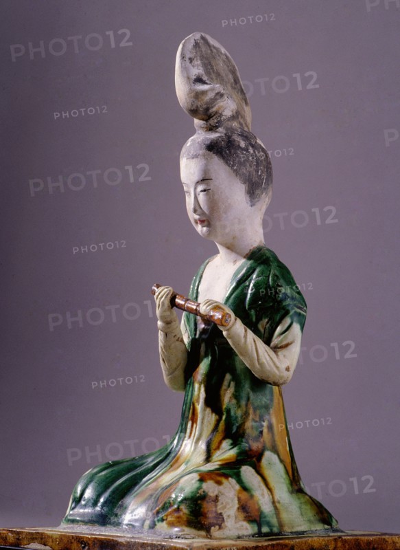 Figure of a kneeling female musician with a distinctive high chignon hairstyle, holding a flute