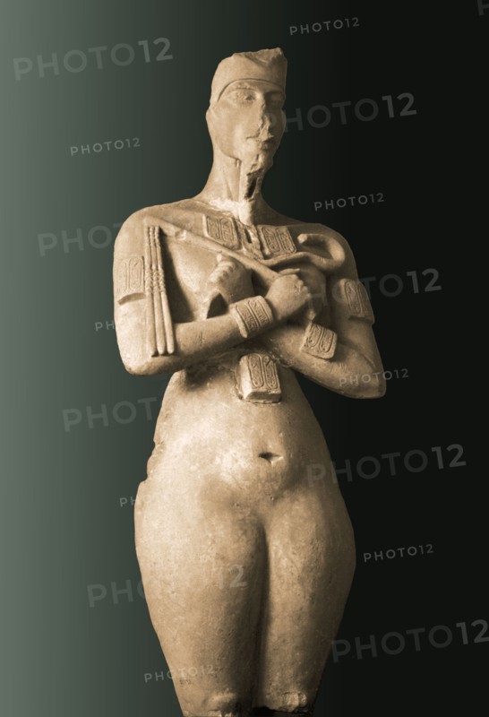 Colossal statue of Akhenaten standing with arms folded holding the flail and heka scepters