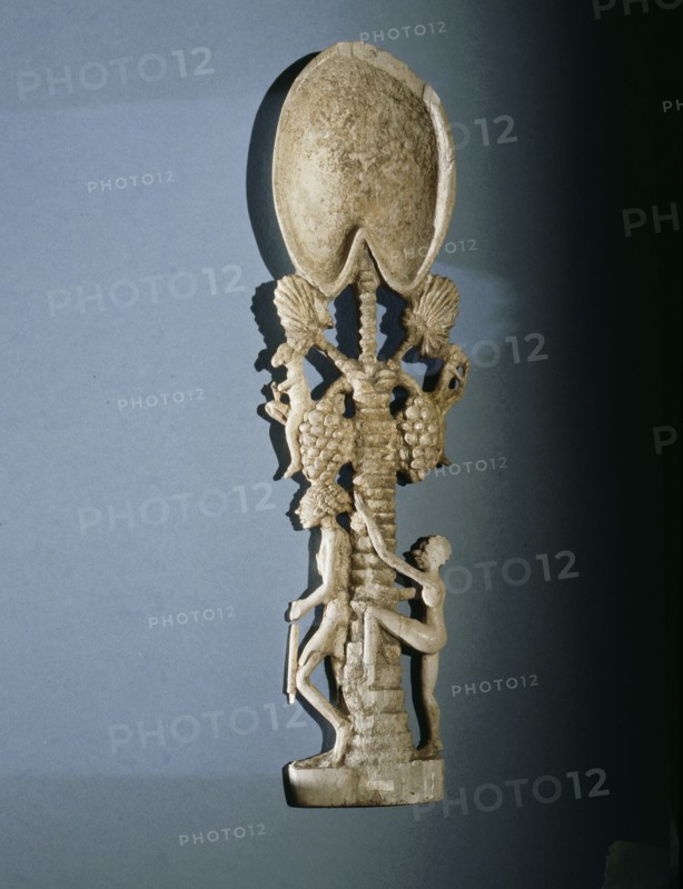 Unguent spoon in the form of a  palm tree with  a guard at  its  foot