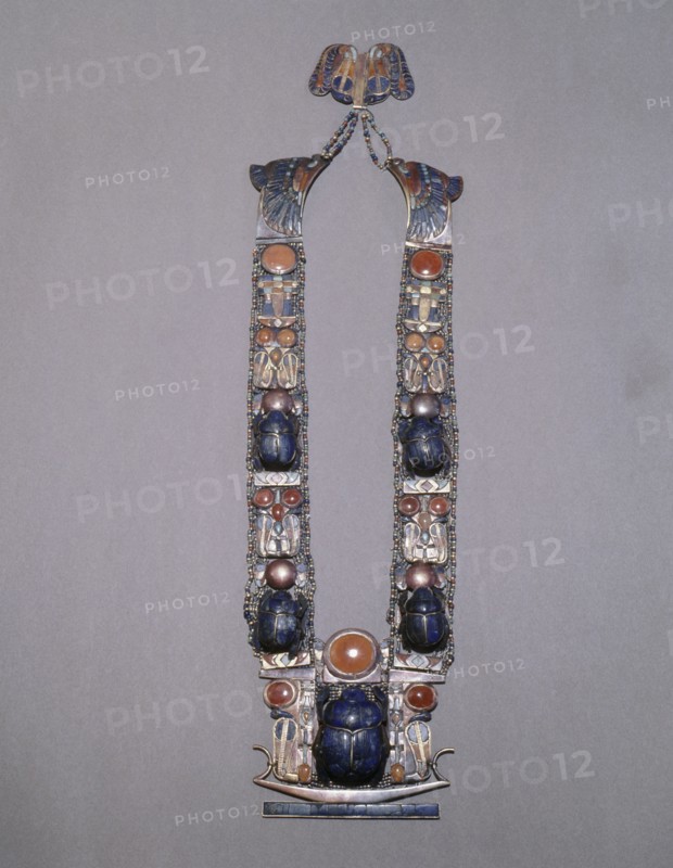 A scarab pectoral from the tomb of Tutankhamun with straps formed from inlaid plaques with uraei (cobras), scarabs & solar discs