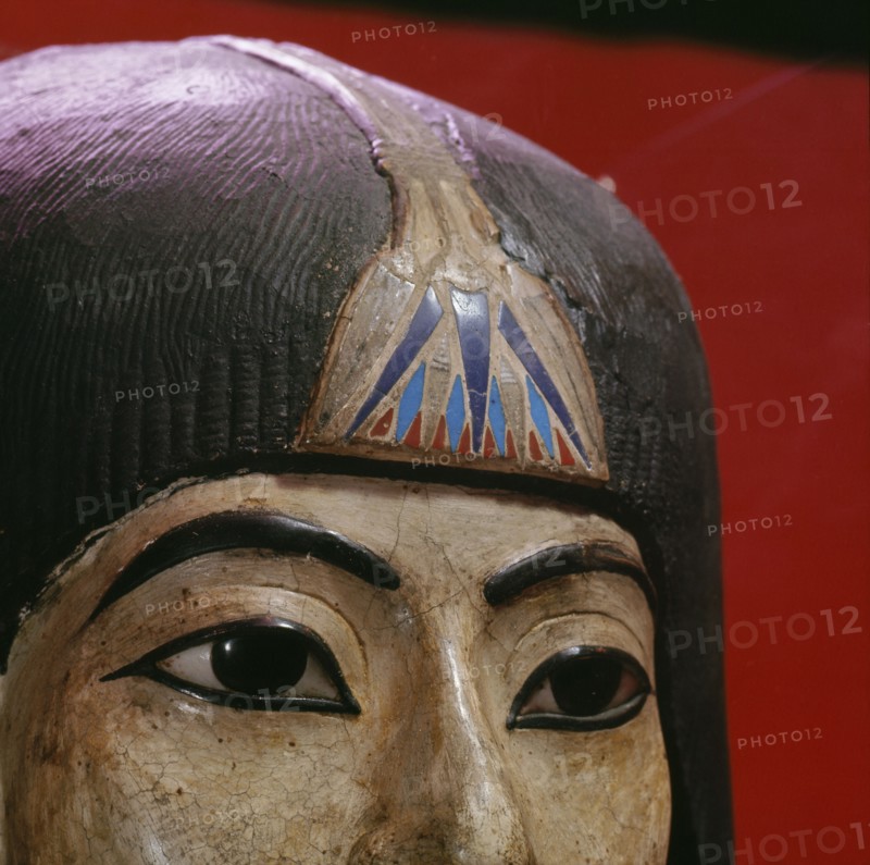 A mummy mask of a man with a heavy wig and an elaborate collar