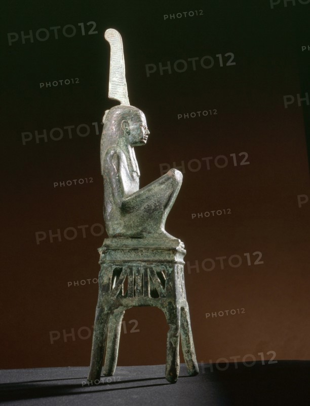 Seated bronze figure of the goddess Maat, wearing a tripartite wig, seated on an openwork throne of winged uraei and Hathor heads