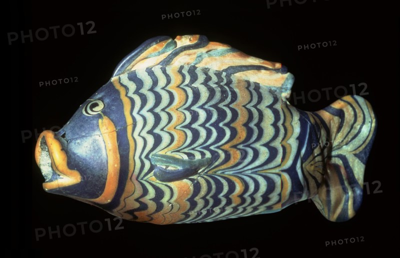 A small painted core glass unguent container in the form of a tilapia fish which was a symbol of rebirth
