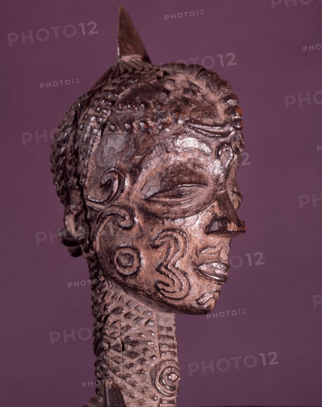 A male figure with elaborate scarification designs on his face and body