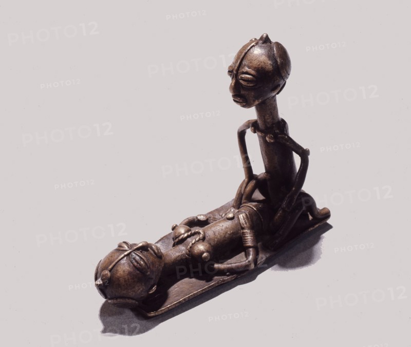 A brass weight which was used for weighing gold dust, representing a man and woman during sexual intercourse