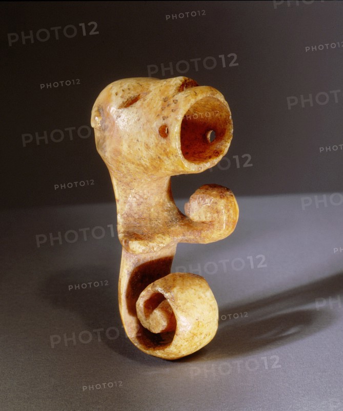 Ivory object, possibly an amulet, carved with a wide mouthed animal face and spiral tail
