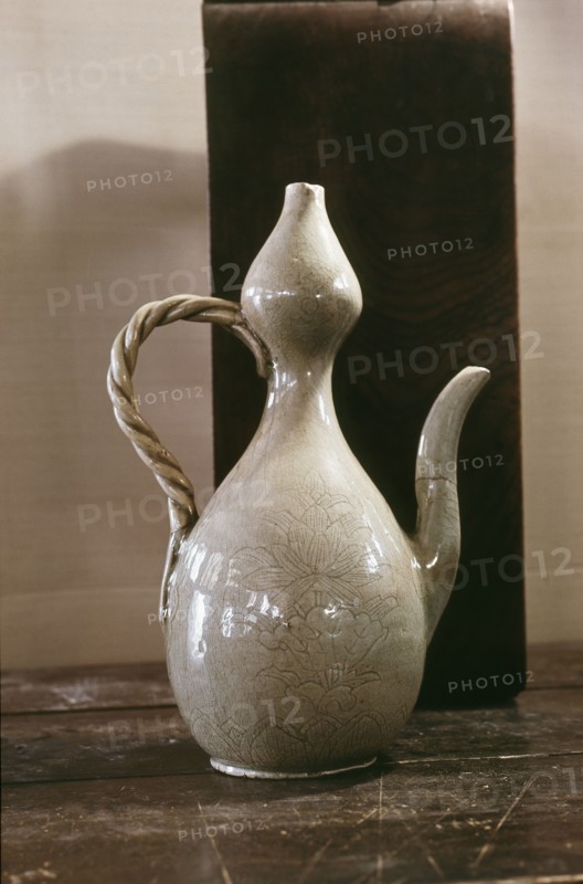 A wine ewer in a double gourd shape with a white glaze, decorated with a large flower, possibly a lotus