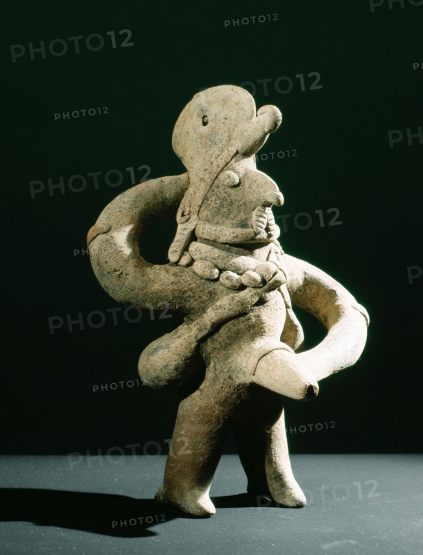 Standing ithyphallic figure, with hat and necklace, holding phallus