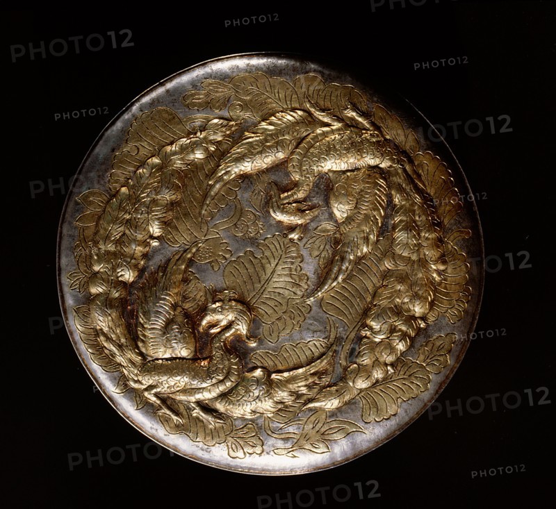 The reverse of a mirror decorated in relief with a pair of phoenixes
