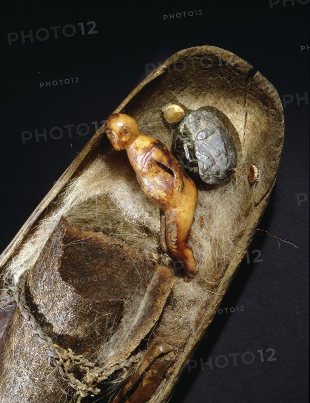 A wooden bowl containing artefacts, including a sea mammal ivory figure, used by a shaman in healing procedures