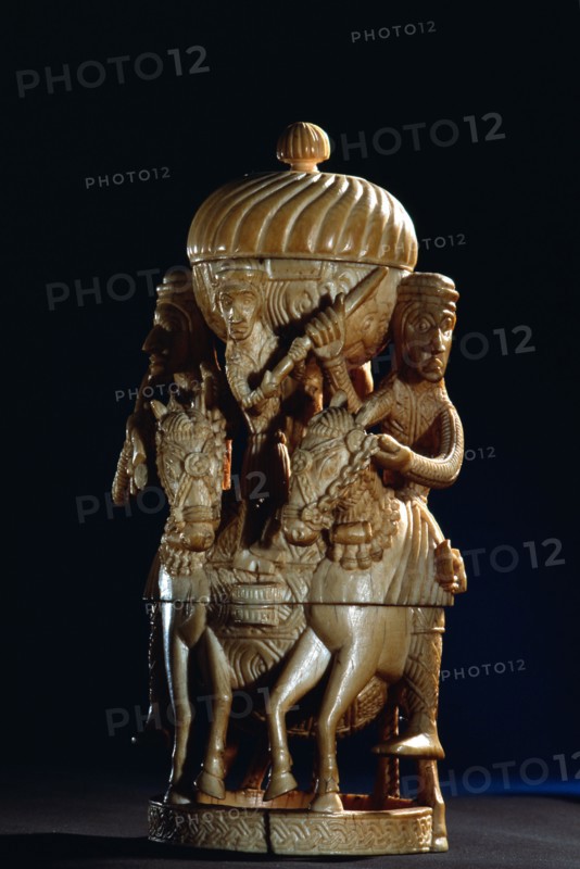 An ivory salt cellar around the base of which are figures of Portuguese noblemen