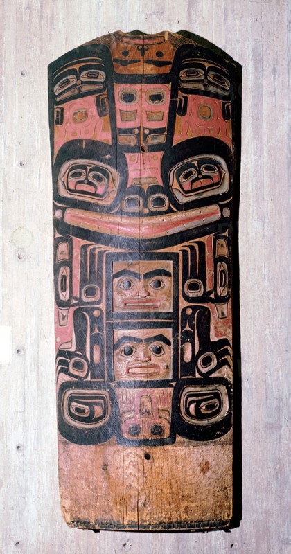 A carved and painted cedar board with a design showing ancestry and social position