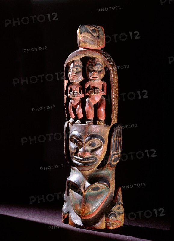 Model totem pole with paired figures below bird crest