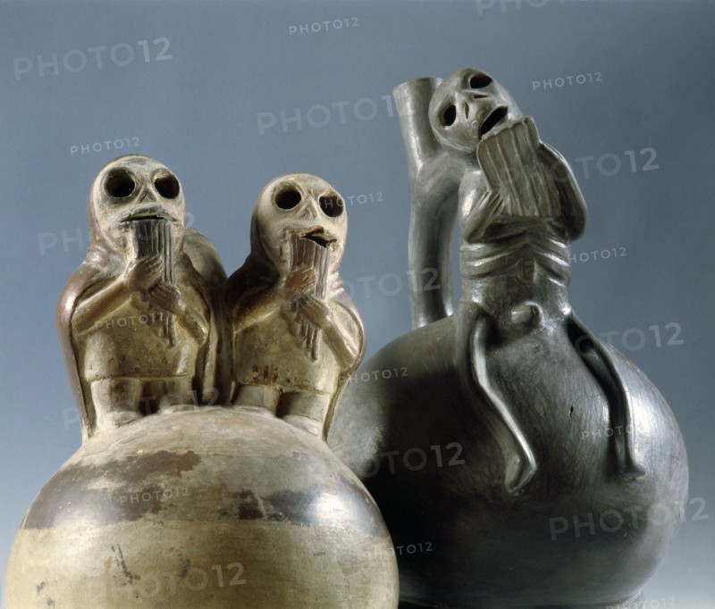 Two stirrup spouted Mochica jars depicting skeletal figures playing typically Andean pan pipes