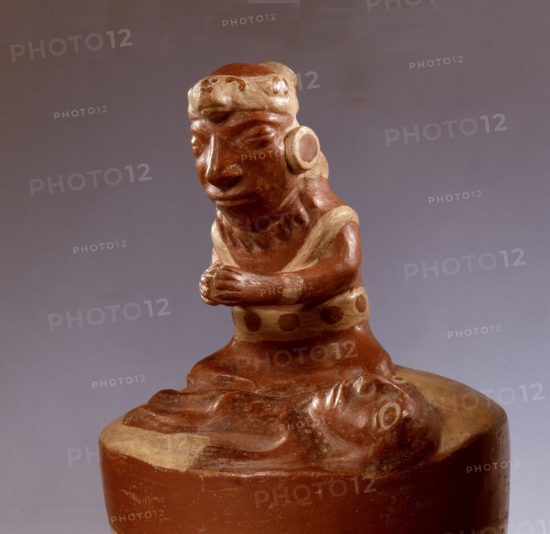 In typically Mochica style, this modelled ceramic shows a priest or shaman engaged in a curing ritual or praying over a deceased person