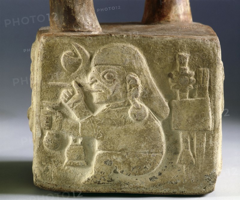 Square, stirrup spouted vessel on one side of which is carved a warrior figure