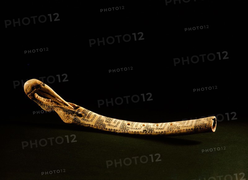 A flute with a bird shaped head and incised with a decorative motif