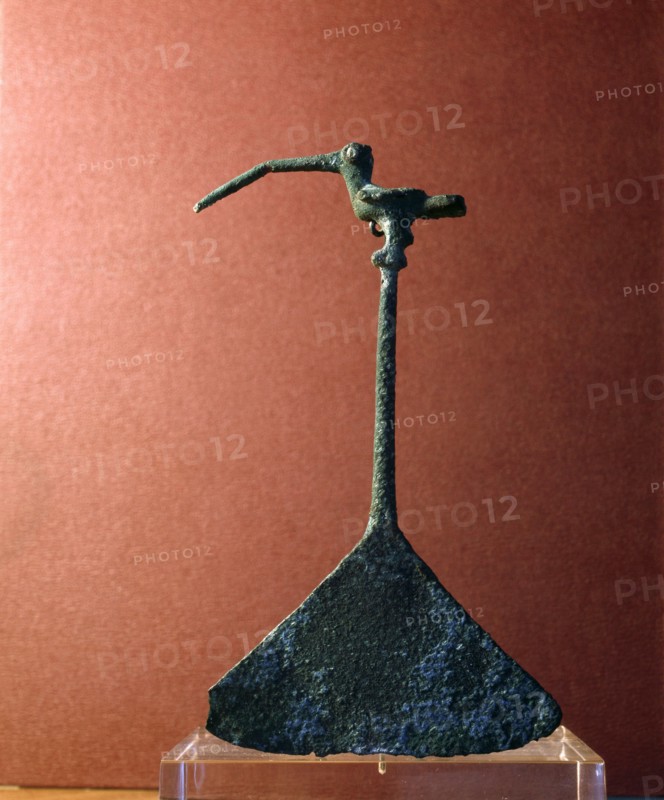 An instrument of beaten metal with a handle in the form of a small, long billed bird