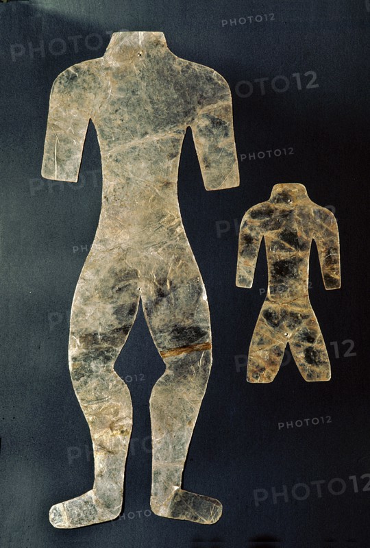 Two silhouettes of mutilated human figures cut from thin sheets of mica