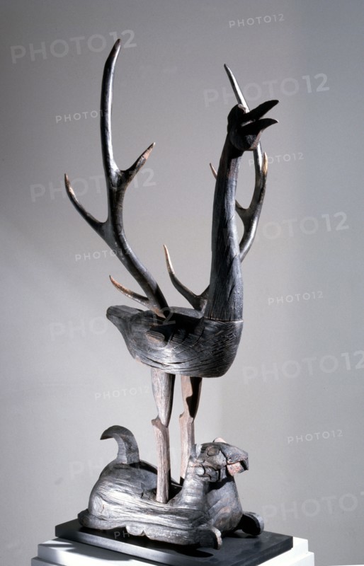 Sculpture of a phoenix with spread wings in the form of deer antlers, resting on a reclining tiger