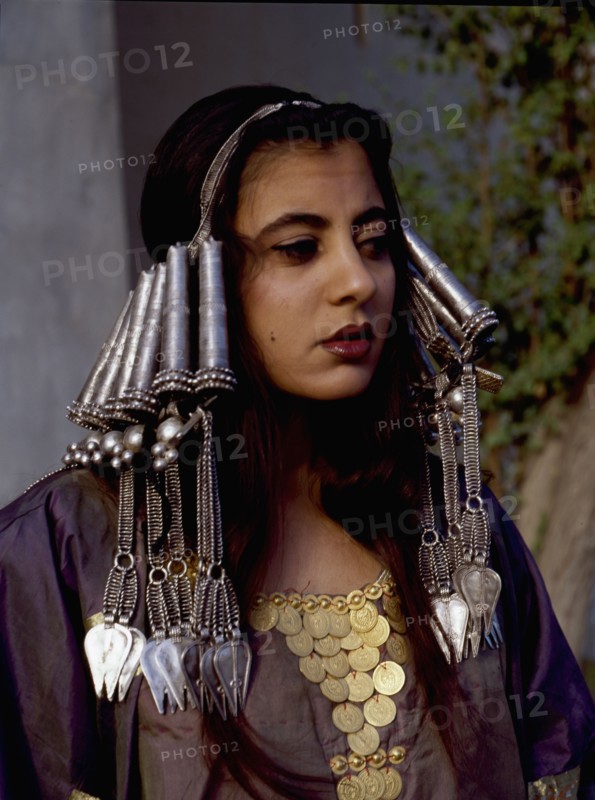 A woman wearing an elaborate silver headdress and traditional costume