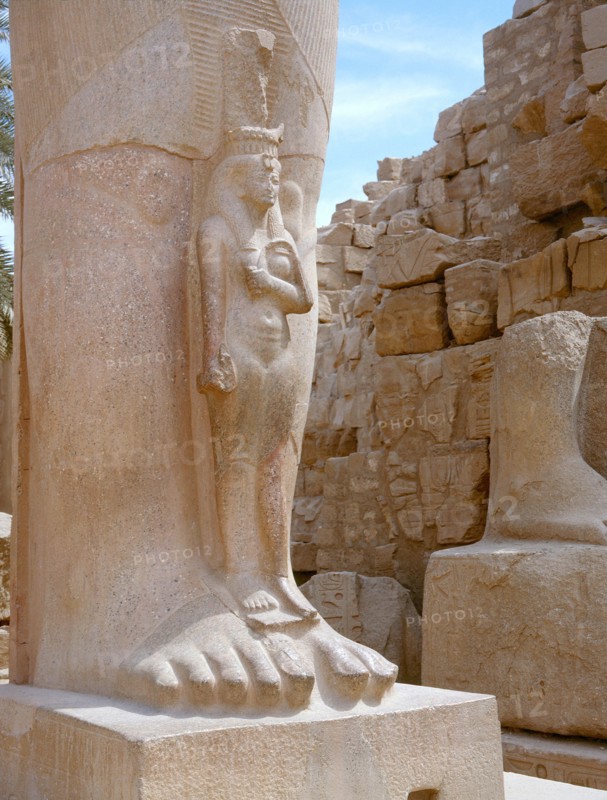 A princess, perhaps Bentanta, standing at the feet of a colossal statue of her father Ramesses II