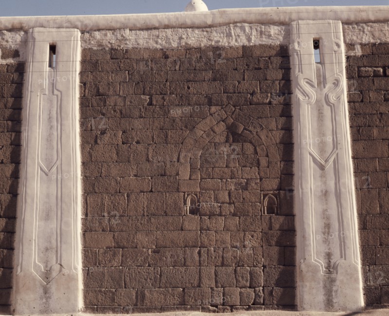Incised plasterwork pilasters set into an old stone wall